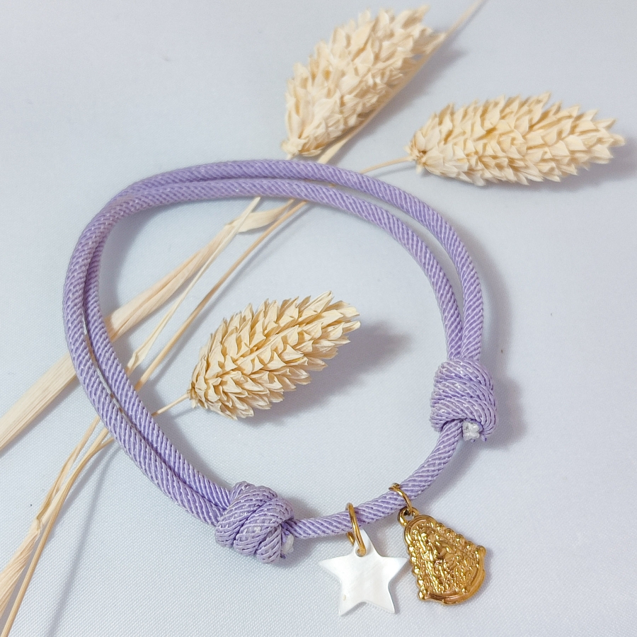 Pulsera de cuerda lila con cruz de nácar y Virgen del Rocío de acero